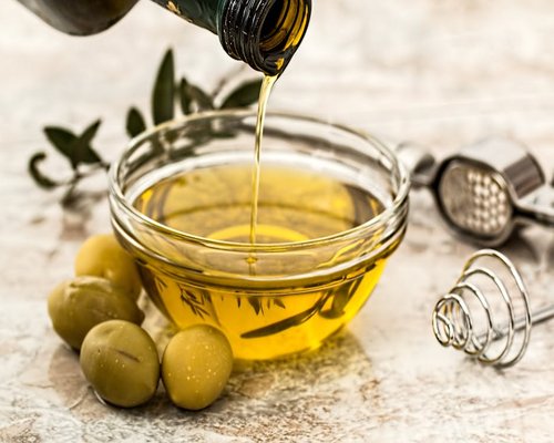 Extra virgin olive oil being poured over a fresh salad